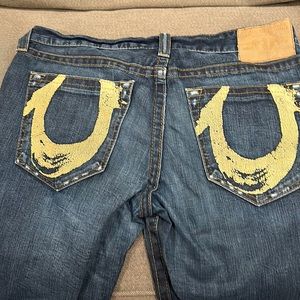 Men’s dark blue True Religion jeans with printed pockets.